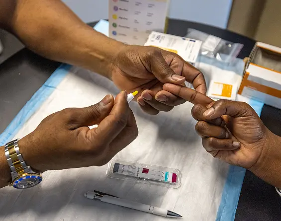 Two hands are shown engaging in a medical procedure, with equipment and materials present on a table.