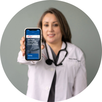 A doctor in a white coat talks on the phone, smiling, with a stethoscope around his neck in a bright office setting.